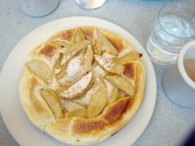 Frissen sült, aranybarna almás felfújt egy fehér tányéron.