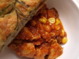 Adag aszalt paradicsomos chilis pulykamell kukoricával, tálalva egy szelet fűszeres kenyérrel.