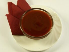 Tál chilimártás egy fehér tányéron, piros szalvétával az alján.