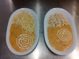 Két fehér ovális tányér Bakonyi gombamártással, az egyiken spagetti, a másikon nokedli kíséretében. A narancssárga színű, krémes mártás tetején fehér tejföllel készült dekoratív mintázat látható.