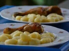 Egy tányéron ízletes, aranyszínű csirkecomb, pikáns gyömbéres-fokhagymás mártással, mellette puha gnocchi.