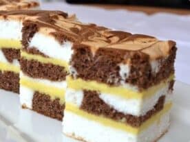 Márványos varázslat: Rétegezett sütemény fehér és barna piskóta rétegekkel és sárga krémmel, márványos mintázattal a tetején.